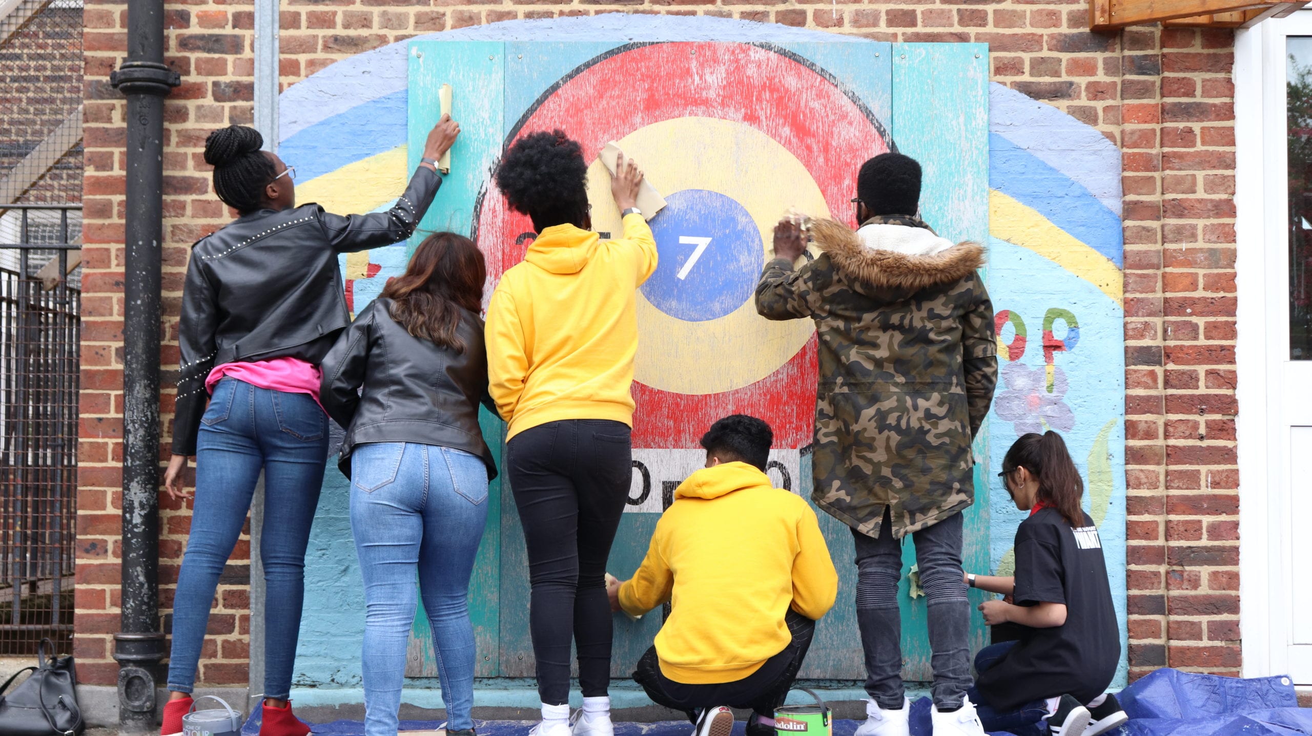 Young people getting involved in social action and painting a community wall.
